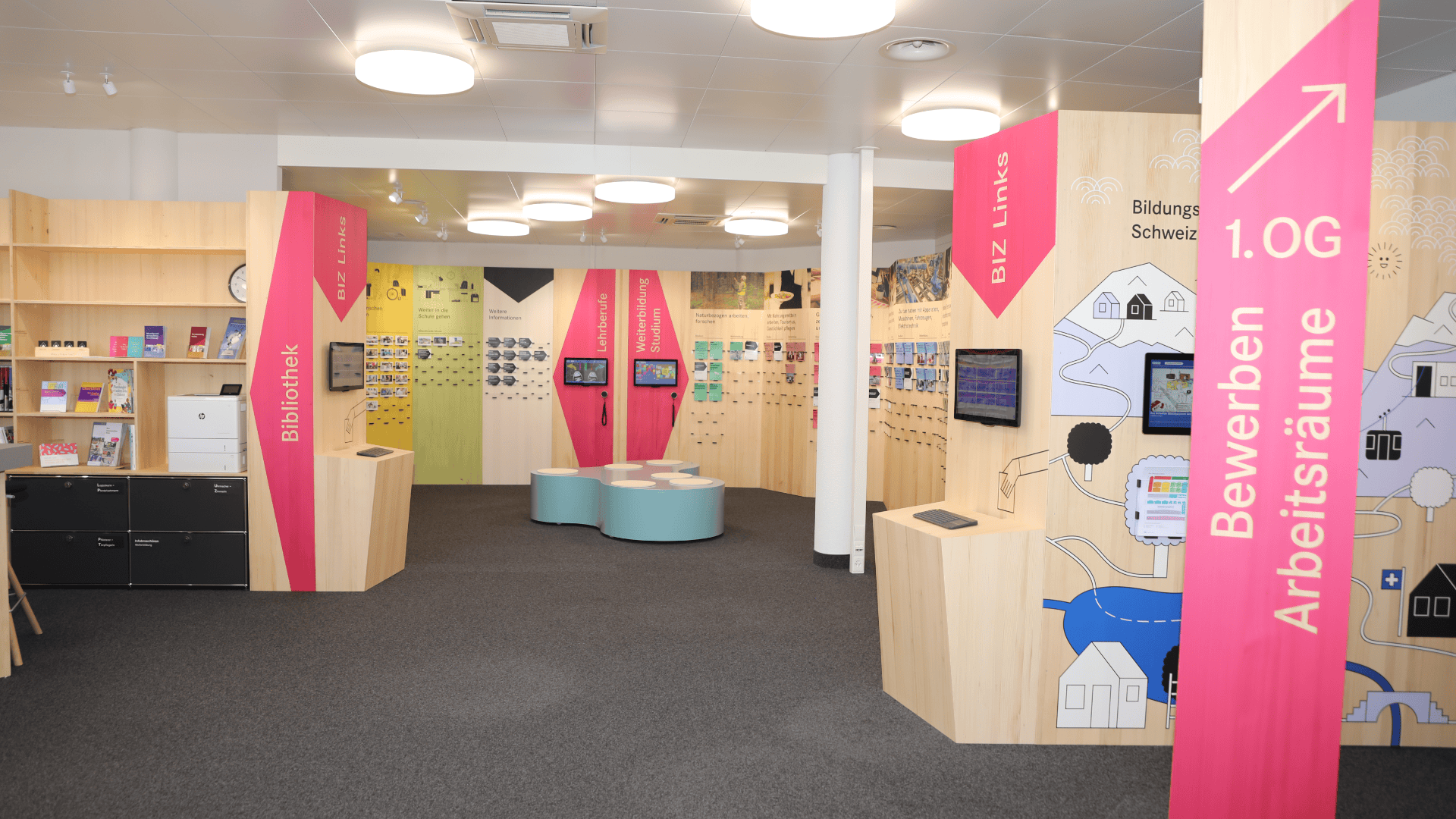 Ein moderner Bibliotheksbereich mit hellen Holzregalen, farbenfrohen Beschilderungen, Büchern, Touchscreens und Informationsanzeigen. Es gibt Arbeitsbereiche und Sitzecken, wobei rosa Banner die verschiedenen Bereiche und Angebote der Bibliothek hervorheben.