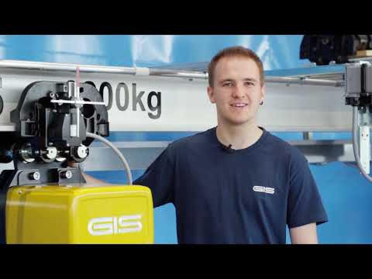 Ein Mann, der ein marineblaues GIS-Hemd trägt, steht neben einer gelben Industriemaschine mit der Aufschrift GIS und einem sichtbaren 2000-kg-Gewichtslimitschild im Hintergrund.