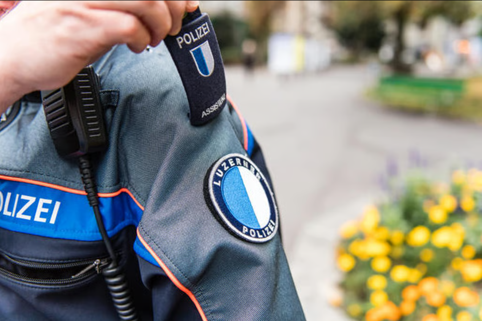 Nahaufnahme eines Ärmelbündchens der Luzerner Polizei mit einem runden Aufnäher, auf dem das blau-weiße Kantonswappen abgebildet ist.