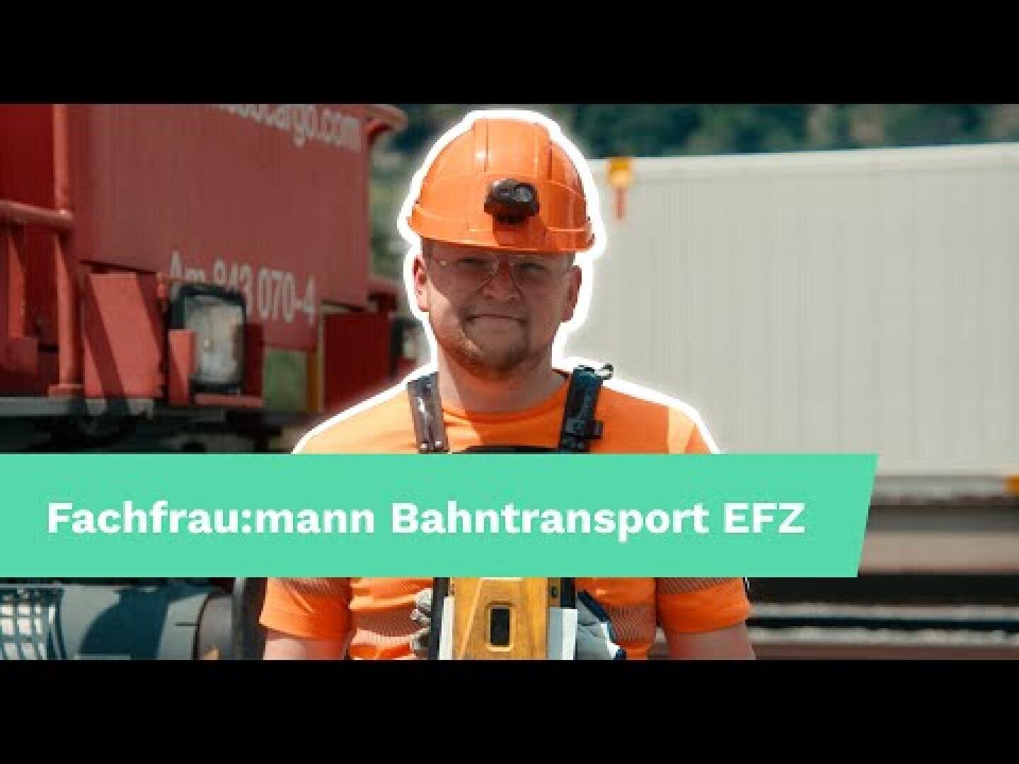 Ein Eisenbahner in orangefarbener Uniform und Helm steht vor einem Zug. Eine grüne Aufschrift quer über dem Bild lautet "Fachfrau:mann Bahntransport EFZ".