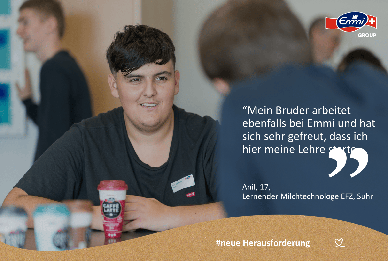 Ein Jugendlicher mit kurzen dunklen Haaren sitzt an einem Tisch mit Kaffeetassen und lächelt eine verschwommene Person im Vordergrund an. Neben ihm ist ein Zitat über seine Lehre bei Emmi zu lesen. In der rechten oberen Ecke ist das Logo der Emmi Gruppe zu sehen.